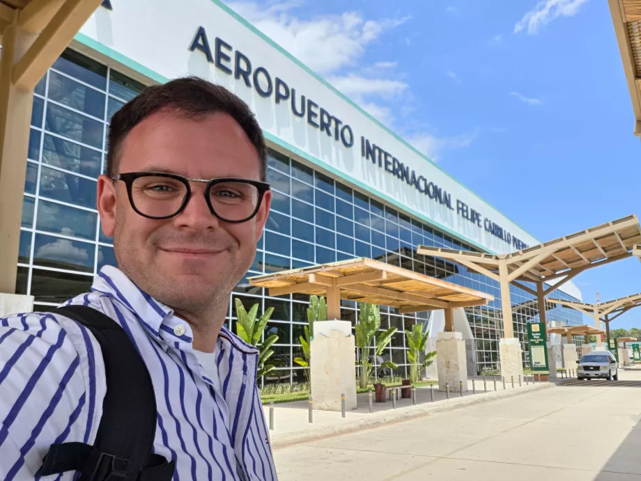 Eu em frente ao terminal do aeroporto de Tulum